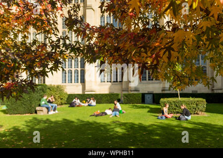 Student of University of Bristol enjoying sunny day sitting or lying on grass, Bristol, UK (students out of focus.  See WPHB19 for students in focus) Stock Photo