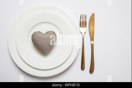 Wedding anniversary dinner table setting, Gold fork and knife on white set of dishes isolated, white background, top view Stock Photo