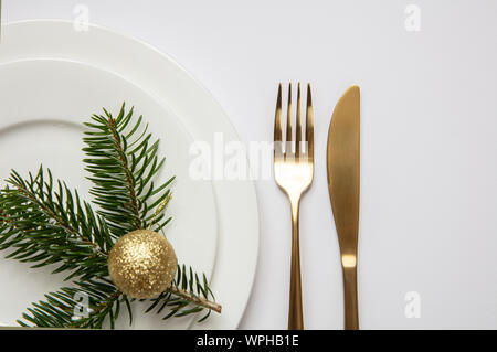 Christmas, new year dinner table setting. Fir tree twig on white set of dishes, white background, top view Stock Photo