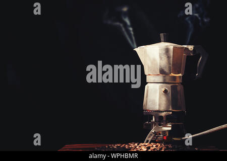 Moka pot old coffee maker and coffee beans on black background Stock Photo