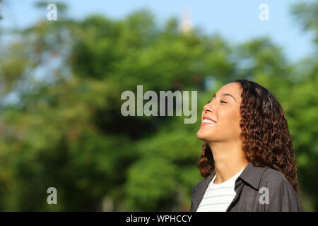 Happy mixed race woman breathing deeply fresh air in a park or forest a sunny day Stock Photo