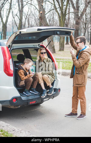 young family packing for car travel. putting bags into trunk Stock Photo