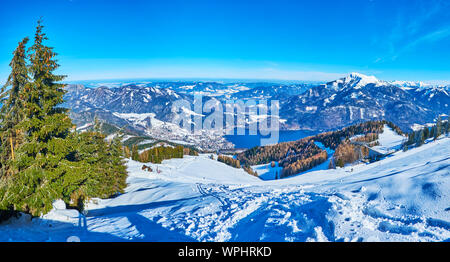 The view from Zwolferhorn on mountains of Eastern Alpine region, Wolfgangsee valley, snowy town of St Gilgen and the Mondsee lake on horizon, Salzkamm Stock Photo