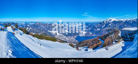 ST GILGEN, AUSTRIA - FEBRUARY 23, 2019: Panorama of snowy Zwolferhorn slope with ski runs, the Wolfgangsee lake and mountains of Eastern Alpine region Stock Photo