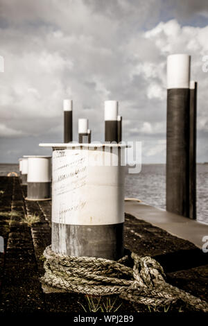 A day at the docks of Nes harbour during a low tide, with pictures of dock equipment such as ropes, poles, wooden posts at the harbourfront Stock Photo