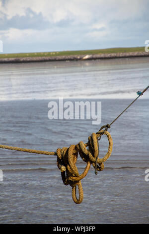 A day at the docks of Nes harbour during a low tide, with pictures of dock equipment such as ropes, poles, wooden posts at the harbourfront Stock Photo