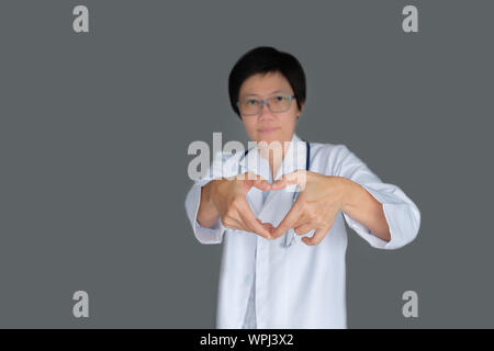 Portrait-A mature Doctor with stethoscope and Heart-shaped hand, looking at Camera on gray background. Stock Photo