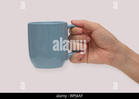Hand holding blue ceramic mug or Coffee cup with shadow isolated on pink background. Stock Photo
