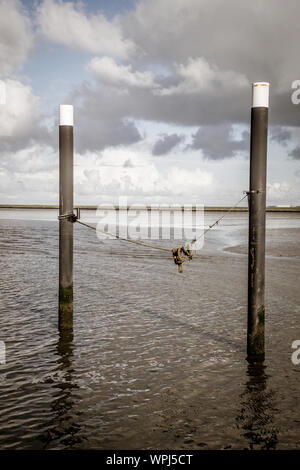 A day at the docks of Nes harbour during a low tide, with pictures of dock equipment such as ropes, poles, wooden posts at the harbourfront Stock Photo