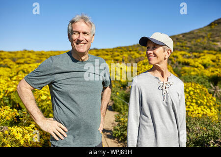 Smiling senior couple standing on mountain against blue sky during summer Stock Photo