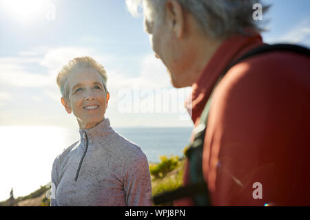 Smiling senior woman looking at man while standing against sky during sunny day Stock Photo