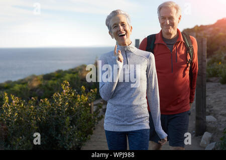 Cheerful senior couple walking on floorboard against sky sunny day Stock Photo