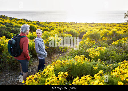 High angle view of senior couple talking while standing on trail by flowers plants against bright sky Stock Photo