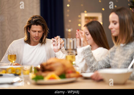 Beautiful family praying over festive dinner at home Stock Photo