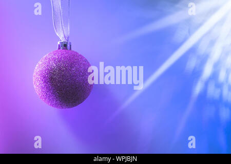 Christmas pink ball with shadow on neon pink and blue. Creative Xmas party background with copy space. Stock Photo