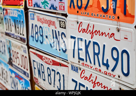 Old discontinued car license plates or vehicle registration numbers from different USA states such as California, Washington, Ohio, Texas. Stock Photo