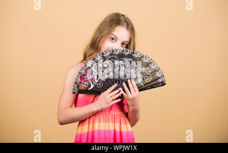 Dances with fan. Girl fanning herself with fan. Air circulation. Art and culture. Handheld fan create airflow. Airflow from handfans increases evaporation. Cooling effect. Folding fans. Acting school. Stock Photo