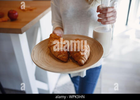 Autumn sseries in the Kitchen, melancholy and warm.. Relaxing in cold weather. red-haired girl holding a tray with pastries and bottle of milk Stock Photo