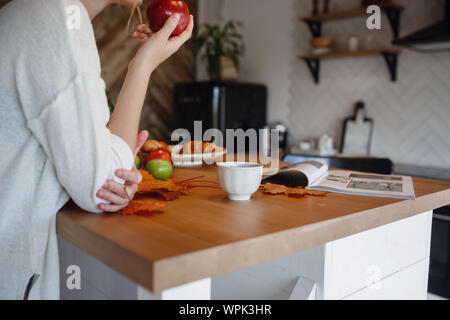 Autumn sseries in the Kitchen, melancholy and warm.. Relaxing in cold weather. red-haired girl enjoying apples in the kitchen Stock Photo