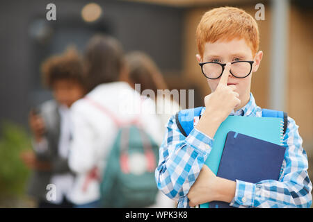 Portrait of red haired boy in eyeglasses holding books and looking at camera he studying at school Stock Photo