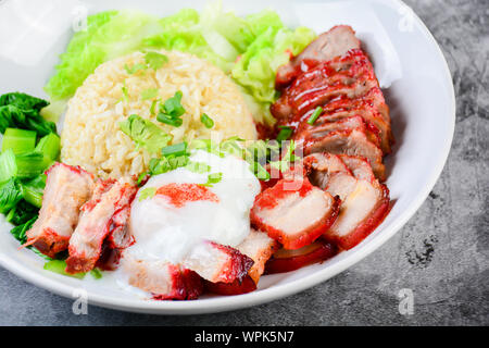 Barbecued red pork and crispy pork in red sauce, served with rice and vegetable on white plate. Stock Photo