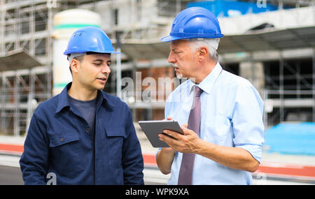 Two architect developers reviewing building plans at construction site Stock Photo