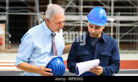 Two architect developers reviewing building plans at construction site Stock Photo