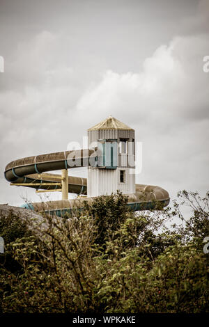 Outdoor shot of an old abandoned indoor swimming pool with its remarakable slide tower in Nes, island of Ameland, in August 2019 Stock Photo