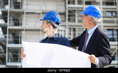 Two architect developers reviewing building plans at construction site Stock Photo