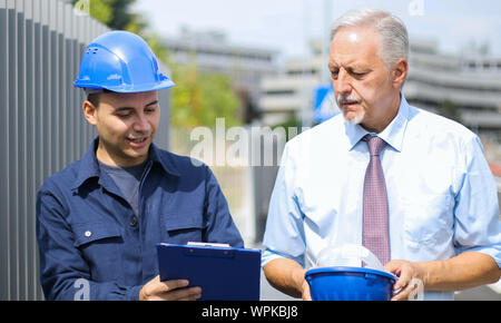 Two architect developers reviewing building plans at construction site Stock Photo