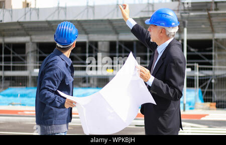 Two architect developers reviewing building plans at construction site Stock Photo