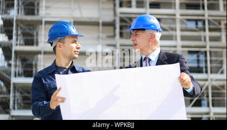 Two architect developers reviewing building plans at construction site Stock Photo