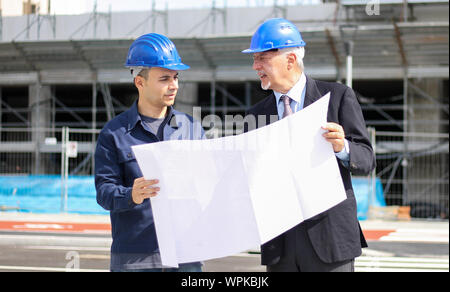 Two architect developers reviewing building plans at construction site Stock Photo