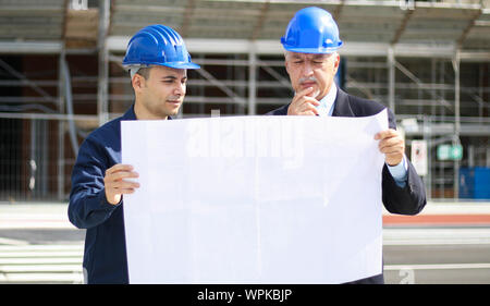 Two architect developers reviewing building plans at construction site Stock Photo