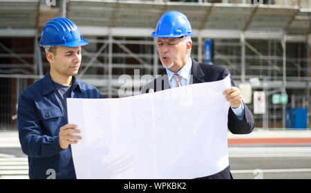 Two architect developers reviewing building plans at construction site Stock Photo