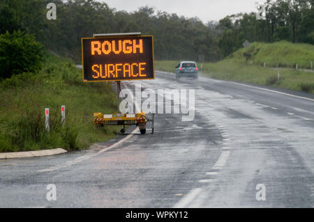 A portable illuminated road sign advising road users on road rough surface  after flash flooding  on the Warrego Highway between Toowoomba and Brisban Stock Photo