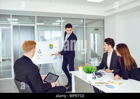 A group of young businessmen are listening to a coach's speech at office. Stock Photo