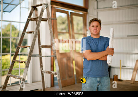 Construction worker writing on a blueprint while a businessman looks on. Stock Photo
