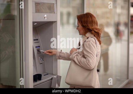 One mature woman, using ATM machine, inserting credit card in machine. Stock Photo
