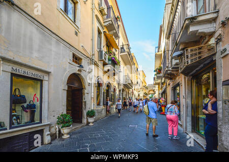 A couple window shops on the Corso Umberto street in the historic Taormina old town on the island of Sicily, Italy in the Mediterranean. Stock Photo