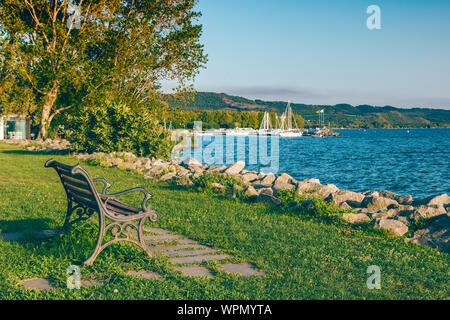 Lonely old wooden bench on sea coast on sunset Stock Photo