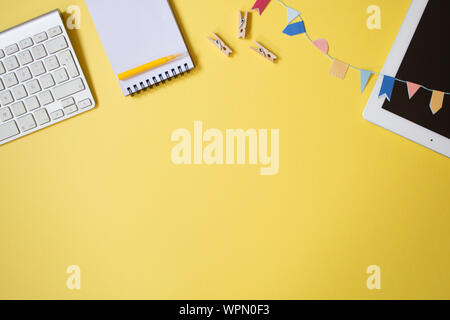 Minimal top view of a youth table desk with laptop, keyboard, notebook, pen and some small clothes pegs. Freelancer workplace concept on pastel colore Stock Photo