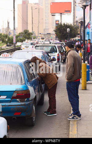 LIMA, PERU - JULY 21, 2013: Unidentified woman asking a taxi for the fare in front of the mall Polvos Azules on Av. Paseo de la Republica Stock Photo