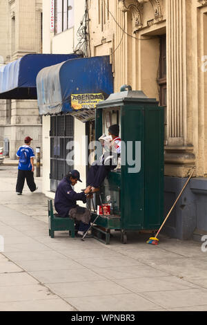 LIMA, PERU - JULY 21, 2013: Unidentified man cleaning the shoes of another person in the city center on July 21, 2013 in Lima, Peru. Stock Photo