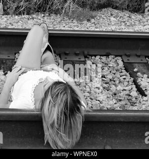 High Angle View Of Young Woman Lying On Railroad Track