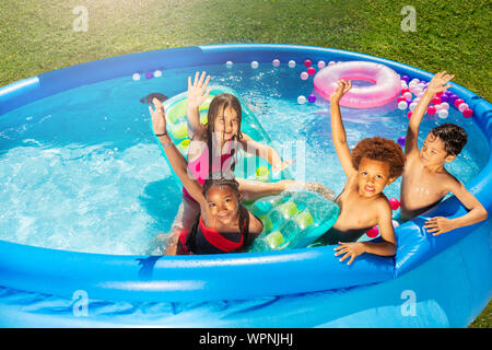 Group of kids play in swimming pool lifting hands Stock Photo