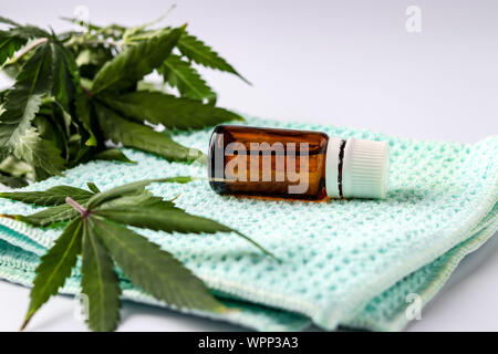 Cannabis oil extract in a glass jar located on a white background with hemp leaves, horizontal orientation, closeup Stock Photo