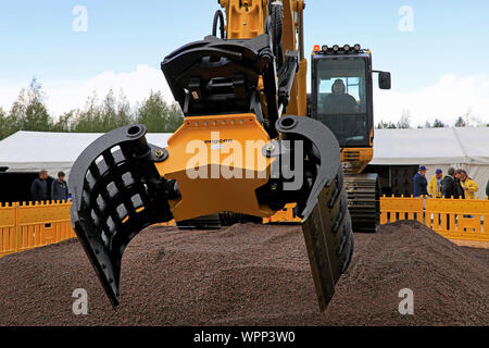 Hyvinkää, Finland. September 6, 2019. Machine operator operating Komatsu HB 215 LC Hybrid excavator with Engcon heavy duty grapple on Maxpo 2019. Stock Photo