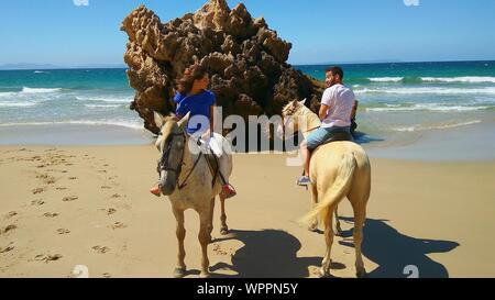 Man And Woman Riding Horses At Beach