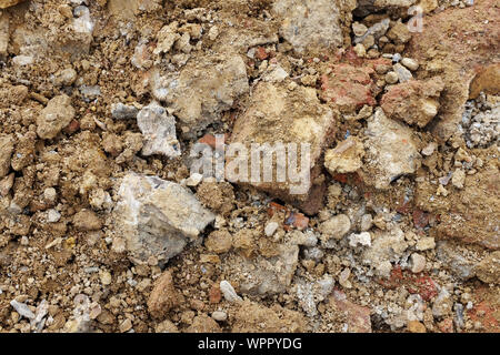 Rough broken concrete and brick, mixed with soil and stones from an excavation - abstract background texture Stock Photo